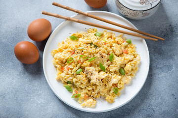 White plate with chinese-style egg fried rice, high angle view on a light-blue stone surface, studio shot