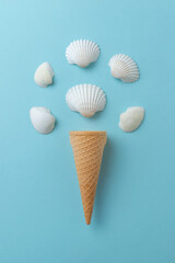 Shellfish ice cream concept on blue surface. Ice cream cone with white shells.