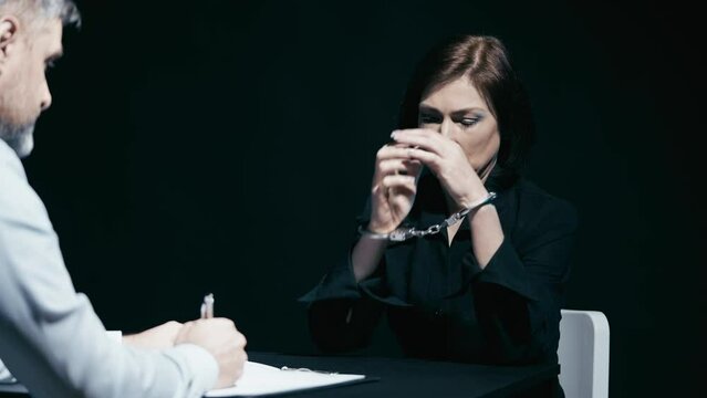 Distressed woman wearing handcuffs crying and shouting at police detective