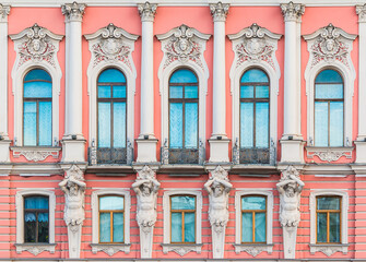 Atlantes and many windows in a row on the facade of the urban historic apartment building front view, Saint Petersburg, Russia
