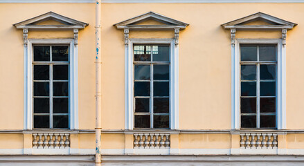 Fototapeta na wymiar Three windows in a row on the facade of the urban historic apartment building front view, Saint Petersburg, Russia 