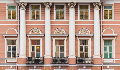 Columns and many windows in a row on the facade of the urban historic apartment building front view, Saint Petersburg, Russia
