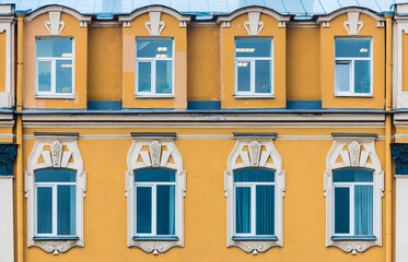 Fototapeta premium Several windows in a row on the facade of the urban historic apartment building front view, Saint Petersburg, Russia 