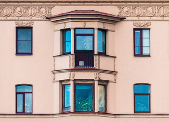 Two bay windows and several windows in a row on the facade of the urban historic apartment building front view, Saint Petersburg, Russia
