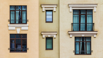 Fototapeta na wymiar Balcony and several windows in a row on the facade of the modern urban apartment building front view, Krasnaya Polyana, Sochi, Krasnodar Krai, Russia 