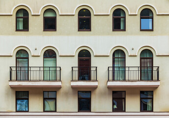 Fototapeta premium Three balconies and many windows in a row on the facade of the modern urban apartment building front view, Krasnaya Polyana, Sochi, Krasnodar Krai, Russia 