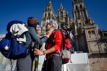 A couple of pilgrims celebrate in front of the cathedral of Santiago that they have reached the end of the journey after walking the Camino de Santiago