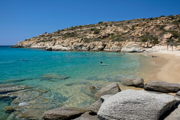 Tourists enjoying the paradisiac beach with turquoise waters and golden sand of Pikri Nero in Ios...