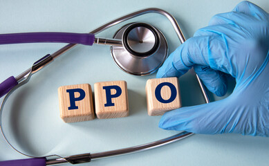 A hand in a medical glove puts cubes with the abbreviation PPO on the background of a stethoscope - obrazy, fototapety, plakaty