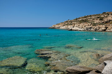 Tourists enjoying the paradisiac beach with turquoise waters and golden sand of Pikri Nero in Ios...