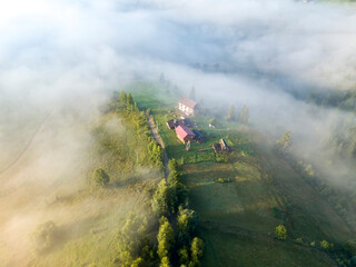 Fototapeta premium Mountain settlement in the Ukrainian Carpathians in the morning mist. Aerial drone view.