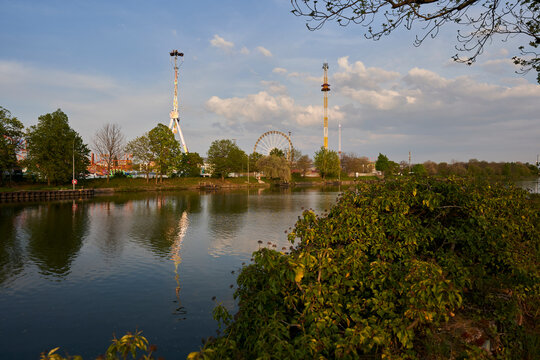 Stuttgart, Germany - April 22, 2022: Spring festival (Fr&uuml;hlingsfest) with Fun rides and carousels by the river at evening. Germany, Stuttgart, Wasen.