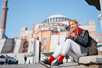 Enjoying vacation in Istanbul. Young traveling woman using smartphone near Hagia Sophia Temple.