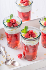 Homemade red jelly served in glass with raspberries.