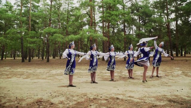 Six young beautiful women are dancing russian traditional dance in summer forest