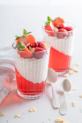 Delicious and creamy red jelly served with berries in glass.