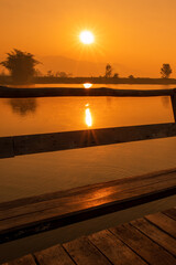 Sunrise time on the lake with wooden seat or bench. with golden light tone.