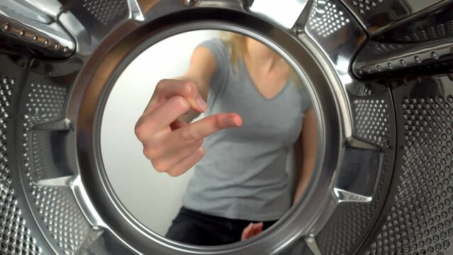 chamber is inside drum of washing machine. woman's hand shows fig and an obscene gesture, fuck you. woman puts her hand inside and shows that she is tired of doing laundry and cleaning. wants to rest
