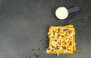 Protein waffle and protein powder from top on dark background