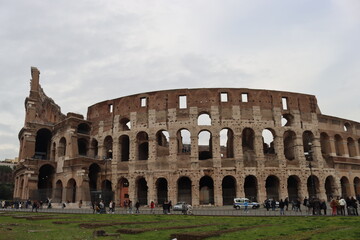Fototapeta na wymiar ROME, ITALY - February 05, 2022: Panoramic view around the Colosseum in city of Rome, Italy. Cold and gray sky in the background. Macro photography of the green parks with the old buildings.