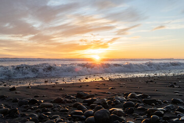 Lens flare horizontal shot of sunset with waves at Concón beach, Chile.