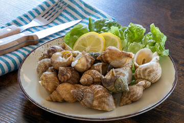 cooked whelks on a plate with salad and lemon