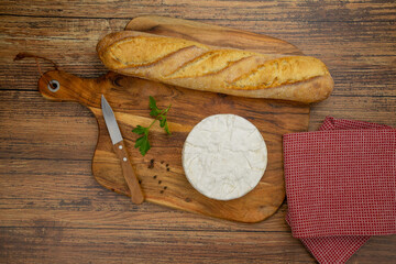 top view of a camembert on a wooden board with bread