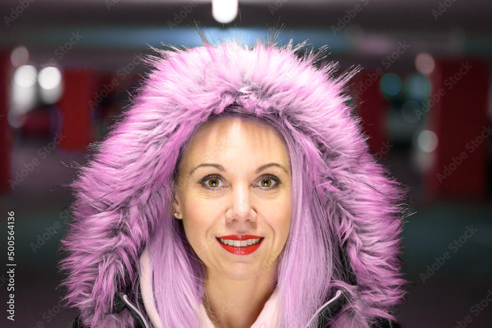 Wall mural Portrait of young woman wearing pink fur coat.