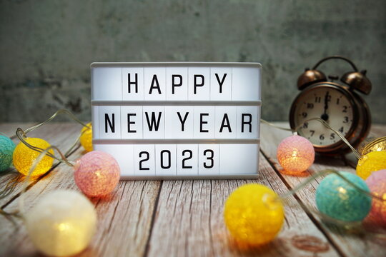 Happy New Year 2023 text on lightbox on wooden background - Powered by Adobe