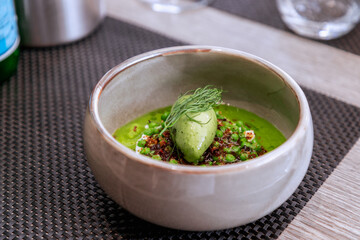Cream soup of green pea with basil ice cream and fried onions. French modern cuisine