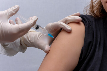 The doctor gives an injection into the girl's shoulder, an injection of a vaccine, a close-up.