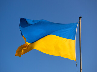The flag of Ukraine on the mast. A flag fluttering in the wind against a blue sky.