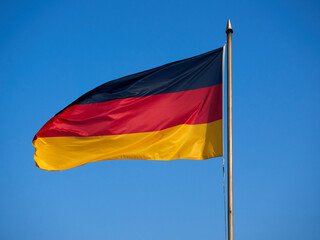 The flag of Germany hanging on the mast. A flag fluttering in the wind against a blue sky.