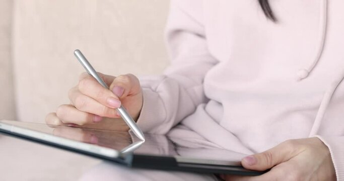 Woman draws with stylus on tablet closeup