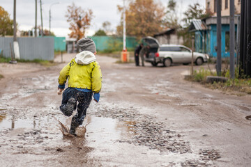 A child runs through a puddle. Children's clothing.
