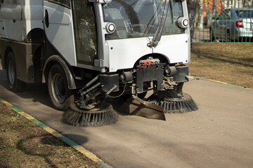 The sweeper is sweeping the asphalt. Cleaning the path with a cleaning vehicle.