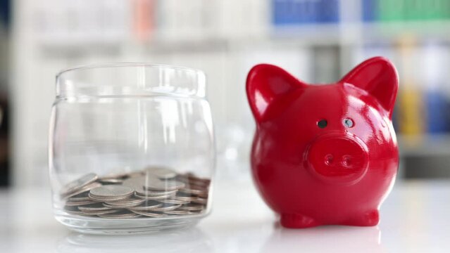 Glass jar piggy bank is filled with coins with piggy bank.