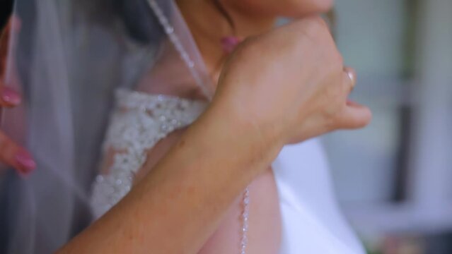 A woman adjusts her daughter's wedding veil. Taking a close-up of her hands