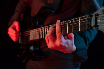 Fototapeta premium Male hands playing electric guitar. Musician man with black guitar at a rock concert