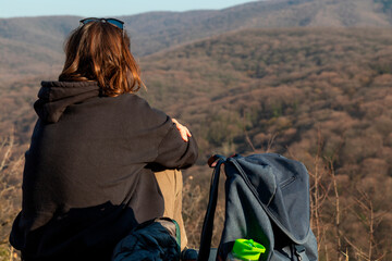 Woman backpacker sits on the hill and looking at mountains.