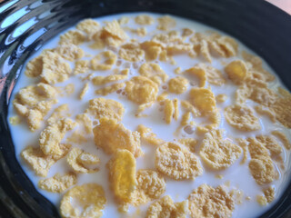 Corn flakes and milk in bowl closeup
