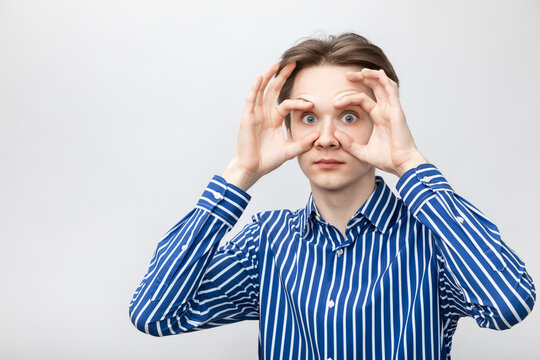 Teenager holding eyes open wide studio shot on gray background