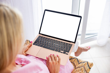 Woman using laptop computer at home, blank white screen mockup