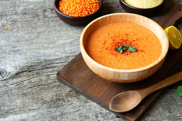Traditional Turkish red lentil soup with ingredients in bowl on rustic table
