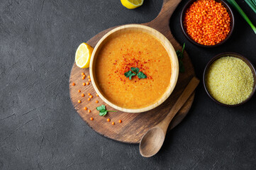 Traditional Turkish red lentil soup with ingredients in bowl on rustic table