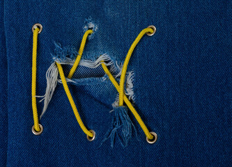 Blue jean with hole and crisscross yellow lacing
