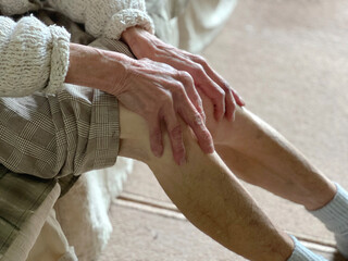 膝を触る高齢女性の手