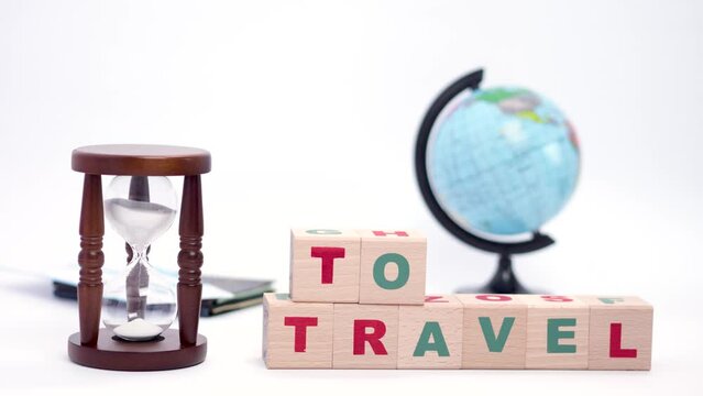 Spinning globe, hourglass, passports with tickets and wooden cubes with words time to travel concept, stop motion animation.