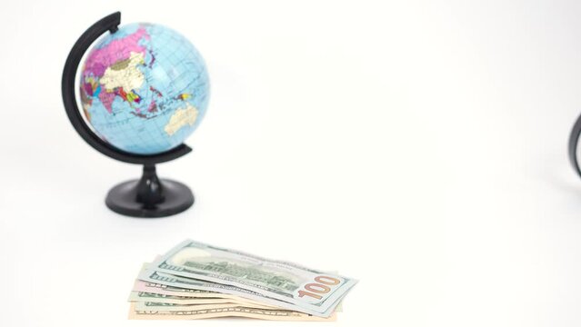 Spinning globe, dollars money, magnifying glass, passports and plane tickets on table, stop motion animation.