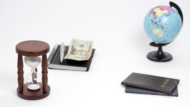 Spinning globe, hourglass, notebook, money, passports, tickets and a toy airplane on white background. Stop motion animation.